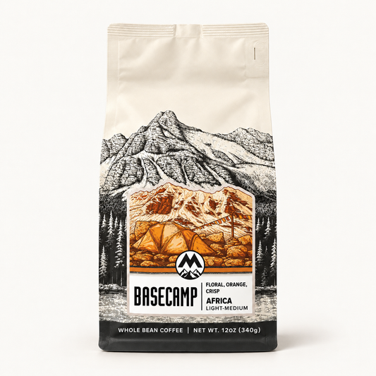 A 12 oz bag of Basecamp Coffee Africa Light-Medium whole bean coffee, featuring a cream-colored background with a black and white mountain illustration and a central orange-brown camping scene.