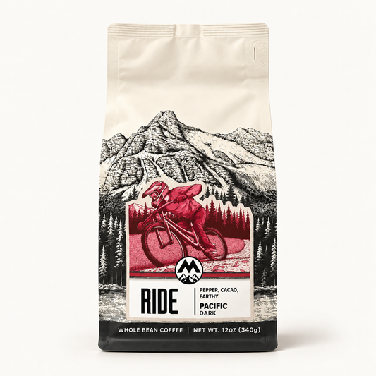 A 12 oz bag of Ride Coffee, Pacific Dark, featuring a black and white mountain illustration with a red graphic of a cyclist in the center, set against a plain white background.